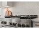 Close-up of a professional-grade stainless steel range and elegant backsplash in a modern, well-lit kitchen at 1608 Legacy Ridge Ln, Wake Forest, NC 27587
