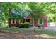 Charming single-story home with red siding, complemented by lush greenery and mature trees at 211 Dwelling Pl, Knightdale, NC 27545
