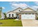 Beige house with stone accents, two-car garage, and well-manicured lawn at 8788 Kenridge Ln, Fuquay Varina, NC 27526