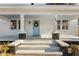 Inviting front porch showcases a light blue door with a wreath, flanked by symmetrical columns and windows at 205 Spring St, Louisburg, NC 27549
