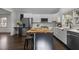 Open kitchen featuring white cabinetry, stainless steel refrigerator, eat-in butcher block island, and modern appliances at 205 Spring St, Louisburg, NC 27549