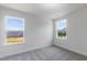 An empty bedroom featuring neutral carpeting and a view from two windows to the neighborhood at 500 Traditions Grande Blvd # 22, Wake Forest, NC 27587