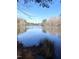 Picturesque lake view with a calm surface reflecting the clear blue sky and surrounding trees at 9201 Sayornis Ct, Raleigh, NC 27615