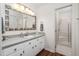Bathroom features white cabinets, grey countertop, decorative mirror, and a tiled shower at 1210 Huntsman Dr, Durham, NC 27713