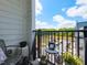 Cozy balcony with metal railing, table and chairs, overlooking parking and green space under a sunny, blue sky at 2313 Gathering Square Ct # 2313, Fuquay Varina, NC 27526