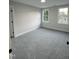 A bright and airy bedroom with neutral walls, plush carpet and natural light from two large windows at 504 Tucker St, Four Oaks, NC 27524