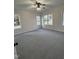 A spacious, bright bedroom with soft gray carpet, ceiling fan and plenty of natural light from three large windows at 504 Tucker St, Four Oaks, NC 27524