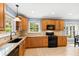 Updated kitchen with granite countertops, wood cabinets, and black appliances at 715 Powell Dr, Raleigh, NC 27606