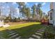 Large backyard with stepping stones and a wooden deck in a well-maintained lawn, surrounded by mature trees at 8005 Sundance Cir, Durham, NC 27713
