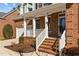 Close-up of the red brick front porch with white railing, and an oval glass on the front door at 8005 Sundance Cir, Durham, NC 27713