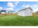 Expansive backyard featuring a lush green lawn, wooden fence, and detached garage or shed in a suburban setting at 129 Mossy Falls Way, Wendell, NC 27591