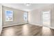 Light filled bedroom with hardwood floors, neutral paint, and two large windows at 129 Mossy Falls Way, Wendell, NC 27591