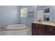 Bright bathroom featuring a soaking tub, vanity with drawers, and large mirror providing a relaxing space at 133 John Winstead Rd, Louisburg, NC 27549