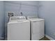 Well-lit laundry room with full-size washer and dryer, and wire shelving at 133 John Winstead Rd, Louisburg, NC 27549