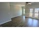 Spacious open-concept living room with wood floors, neutral paint, and a door to the balcony at 203 Broomgrove Way, Wake Forest, NC 27587