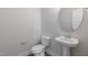 This well-lit half bath features a pedestal sink, round mirror, and modern fixtures at 2117 Treelight Way, Wendell, NC 27591