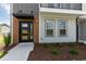 Home exterior showcasing modern entry door, black accents, complemented by professionally landscaped grounds at 2117 Treelight Way, Wendell, NC 27591