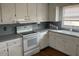 Kitchen boasts white cabinets, gray countertops, and stove at 8110 Nc 210 N, Angier, NC 27501