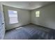 An empty bedroom featuring a gray carpet, white walls, and two windows at 136 Parker Ln, Mebane, NC 27302