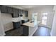 Stylish kitchen features a center island with a sink, black cabinetry and stainless steel appliances at 205 Broomgrove Way, Wake Forest, NC 27587