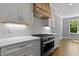 Modern kitchen with stainless steel range and hood, white cabinets, quartz counters, and hardwood floors at 3923 Cedar Knolls Dr # 12, Youngsville, NC 27596