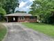 Cozy single-story brick home featuring an attached carport and a well-maintained front yard with mature trees at 404 W Ninth St, Siler City, NC 27344
