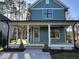 Charming two-story home showcasing a covered porch with white pillars and teal siding at 715 Heidelberg St, Durham, NC 27704