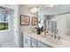 A double sink bathroom with quartz countertop, framed artwork, and a window with view to the outside at 1224 Hardin Hill Ln, Knightdale, NC 27545