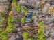 This is an aerial view of a home surrounded by foliage with a long driveway, fire pit and outbuilding at 497 Turn Key Way, Pittsboro, NC 27312