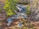 Aerial view of the home with a large parking area, fire pit area, outbuilding, and a wooded landscape at 497 Turn Key Way, Pittsboro, NC 27312