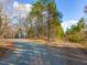 Long gravel driveway leading to the home with mature trees, wooded areas, and a blue sky at 497 Turn Key Way, Pittsboro, NC 27312