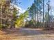 Long gravel driveway with mature trees and wooded areas surrounding the home, a beautiful drive at 497 Turn Key Way, Pittsboro, NC 27312