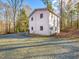 Two-story home with gravel driveway, surrounded by trees, and with a small garden area at 497 Turn Key Way, Pittsboro, NC 27312