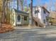 View of the two-story home and outbuilding, surrounded by mature trees and featuring a gravel driveway at 497 Turn Key Way, Pittsboro, NC 27312