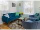 Bright living room with a tufted blue sofa, two chairs, and two windows with sheer curtains at 497 Turn Key Way, Pittsboro, NC 27312