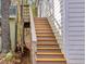 Exterior stairs lead to the second story of this cozy home with wooden steps and white railing at 497 Turn Key Way, Pittsboro, NC 27312