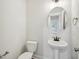 Charming powder room featuring a pedestal sink, round mirror, and modern fixtures, adjacent to mudroom at 18 Hewitt Woods Dr, Clayton, NC 27527