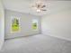 Bright bedroom featuring plush carpet, a ceiling fan, and large windows with green outdoor views at 18 Hewitt Woods Dr, Clayton, NC 27527