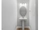Powder room featuring a pedestal sink, oval mirror, and modern lighting fixtures at 257 North Maple Walk Dr # 218, Garner, NC 27529