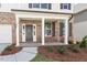 Inviting front porch with brick accents, white columns, a dark front door, and landscaped garden bed at 257 North Maple Walk Dr # 218, Garner, NC 27529