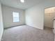 A bright bedroom showcases a neutral carpet, white walls, a window, and an adjacent walk-in closet at 4321 Darius Ln # 23, Fuquay Varina, NC 27526