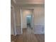 Open hallway view with a partial view of a bathroom, showcasing wood-look flooring and decorative wall paneling at 93 Ausban Ridge Ln # 033, Four Oaks, NC 27524