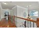 Elegant upper hallway with hardwood floors, wrought-iron railing, and a view of the grand entryway at 10837 Round Brook Cir, Raleigh, NC 27617