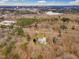 Aerial shot captures the property nestled amongst trees, with a lake and city skyline in the distance at 1126 Trailwood Dr, Raleigh, NC 27606
