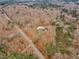 An aerial view displays a home surrounded by a dense forest, with a road winding through the trees at 1126 Trailwood Dr, Raleigh, NC 27606