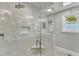 Modern shower featuring stone tiling, a built-in seat, and a glass door at 1126 Trailwood Dr, Raleigh, NC 27606