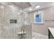 Modern shower featuring stone tiling, a built-in seat, and a glass door at 1126 Trailwood Dr, Raleigh, NC 27606