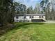 Home exterior with a gravel driveway and large front yard surrounded by mature trees, creating a private setting at 3050 Bennett Siler City Rd, Bennett, NC 27208