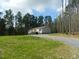 Home exterior with a gravel driveway and large front yard surrounded by mature trees, creating a private setting at 3050 Bennett Siler City Rd, Bennett, NC 27208