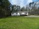 Home exterior with a gravel driveway and large front yard surrounded by mature trees, creating a private setting at 3050 Bennett Siler City Rd, Bennett, NC 27208